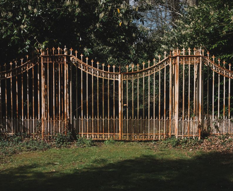 A metal driveway gate beside a masonry post